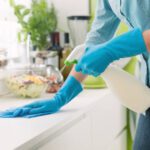 House Maid cleaning and polishing the kitchen worktop with a spray detergent, housekeeping and hygiene concept