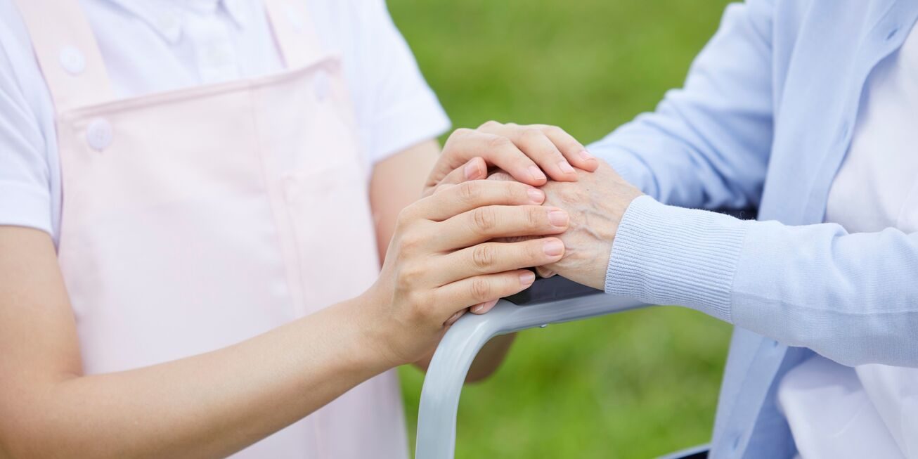 Private caregiver gently holding the hand of a patient, offering comfort and compassionate support.